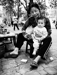 A woman with a little child sitting at a street food shop.